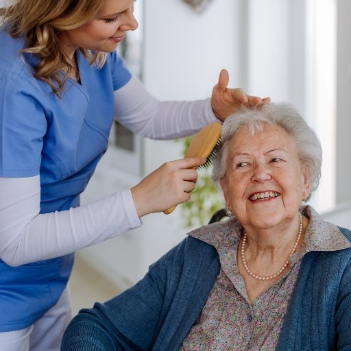 Pflegekraft hilft Seniorin beim Frisieren