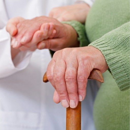 Pflegekraft stützt Seniorin beim Gehen mit Gehstock